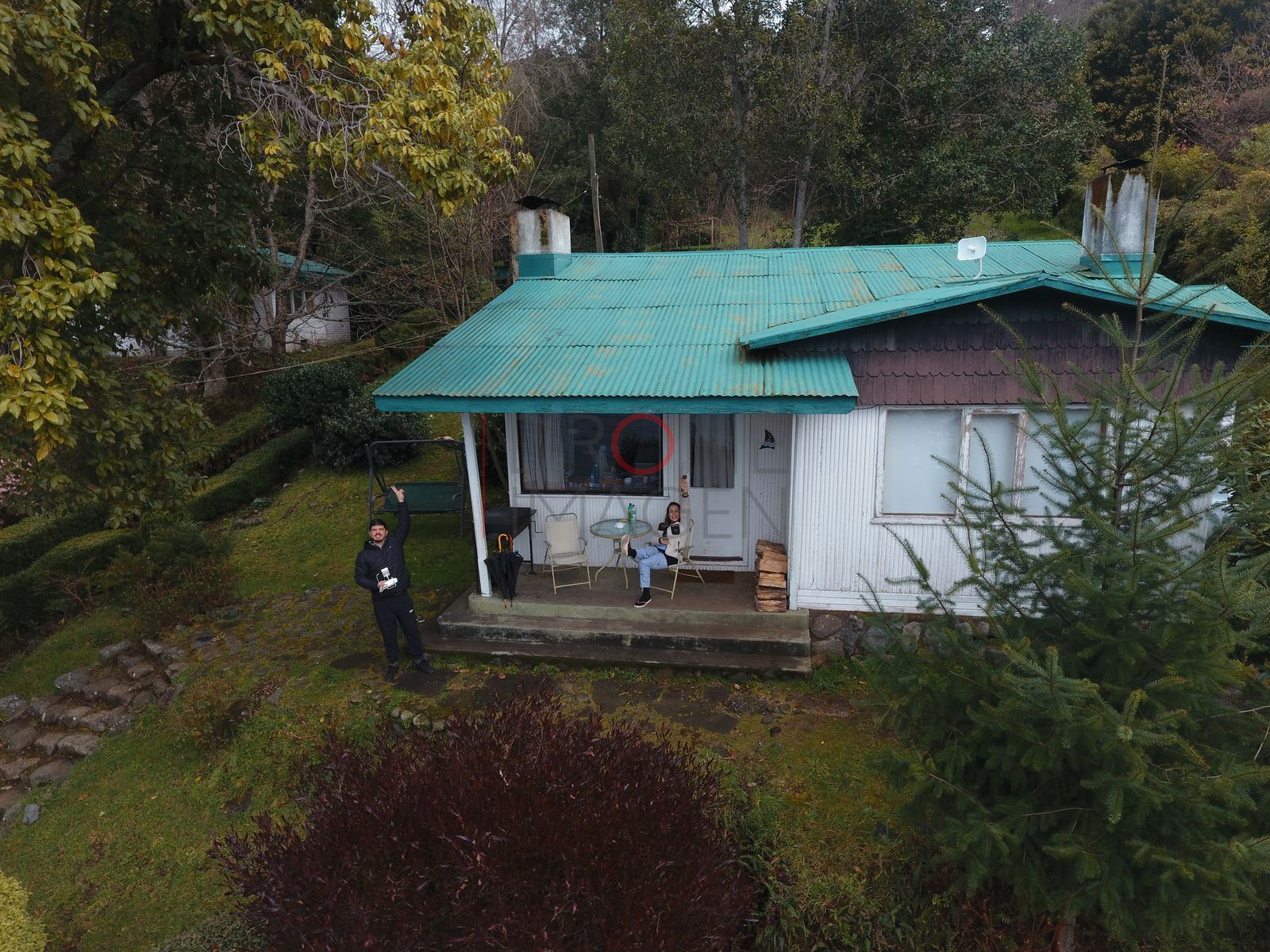 Casa con techo turquesa y personas, lago Ranco