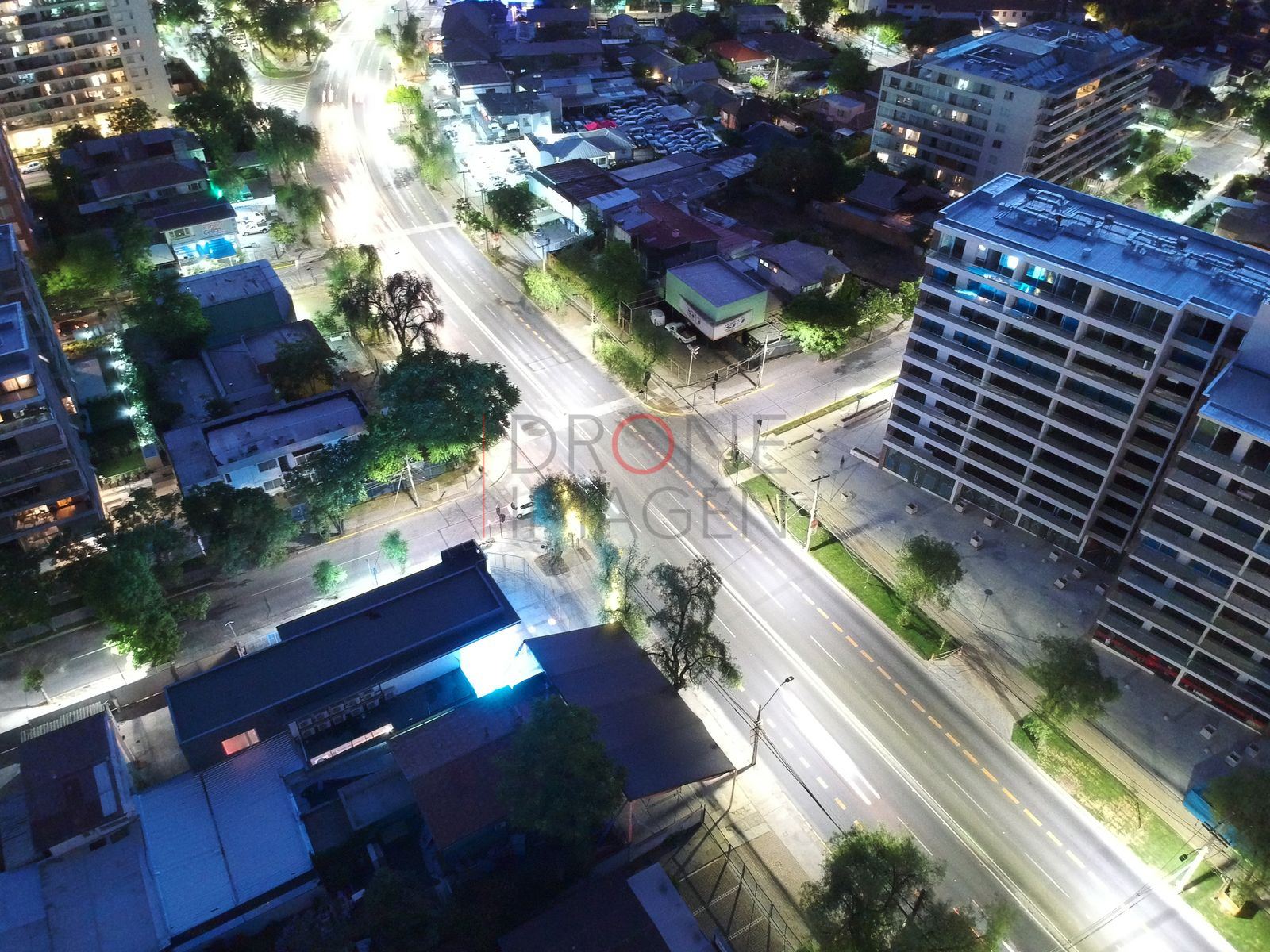 Calle iluminada y árboles en hora azul, Las Condes