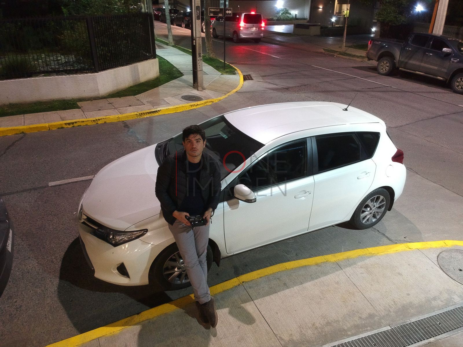 Persona junto a un auto blanco de noche, Las Condes