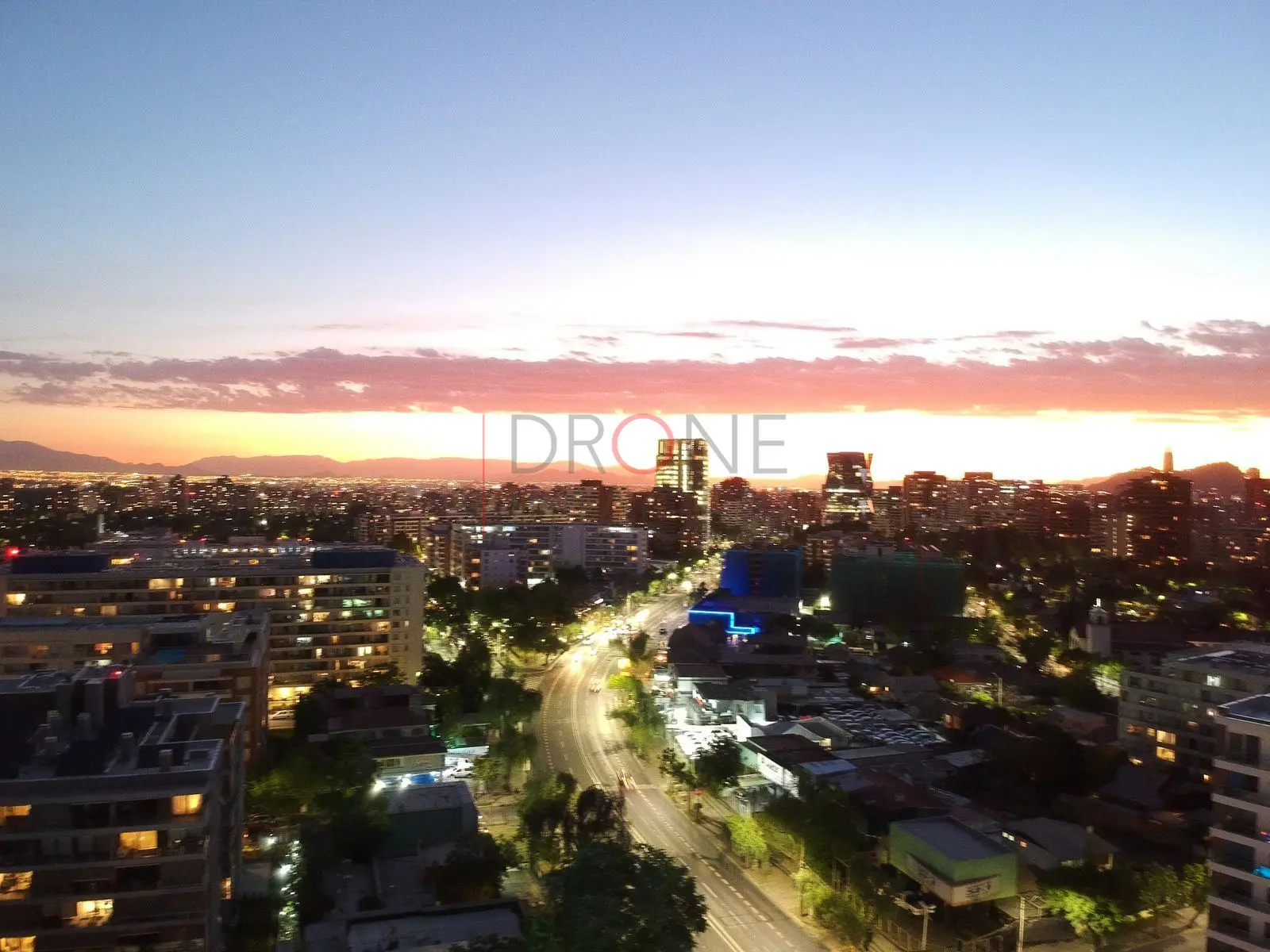 Avenida iluminada al atardecer, Las Condes · vista aérea oblicua