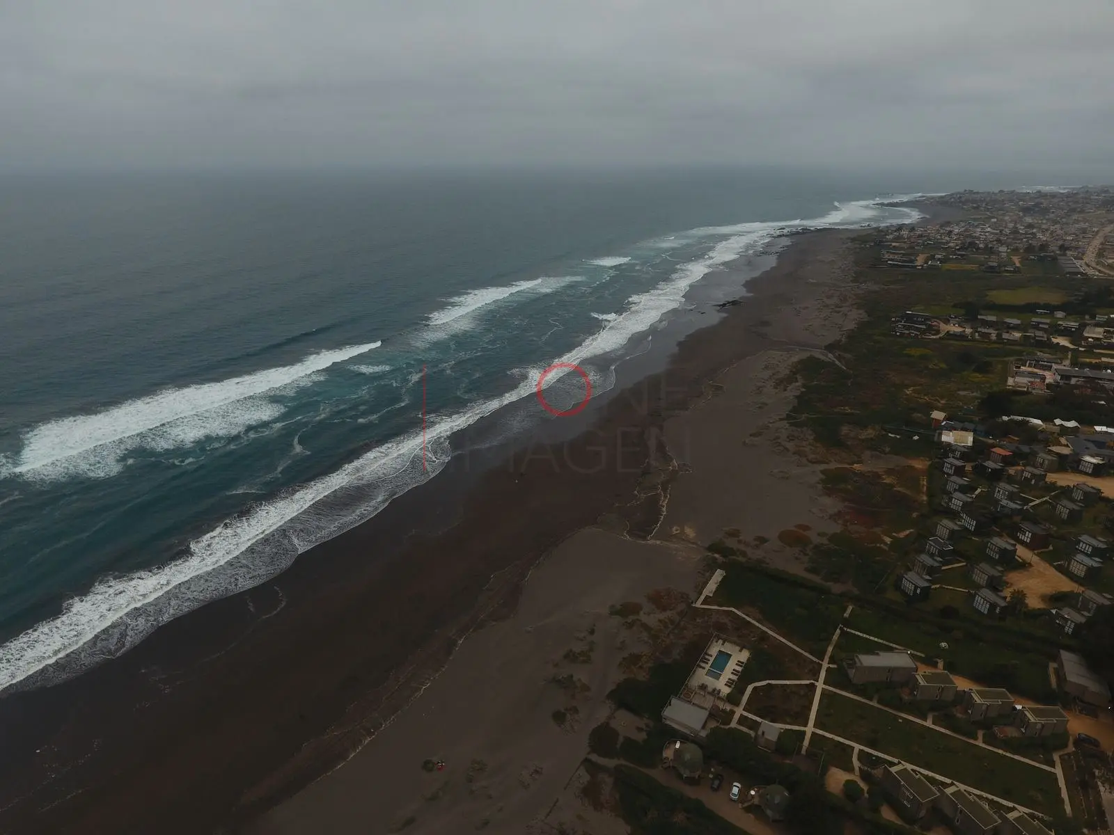 Playa de arena oscura y caserío, Pichilemu