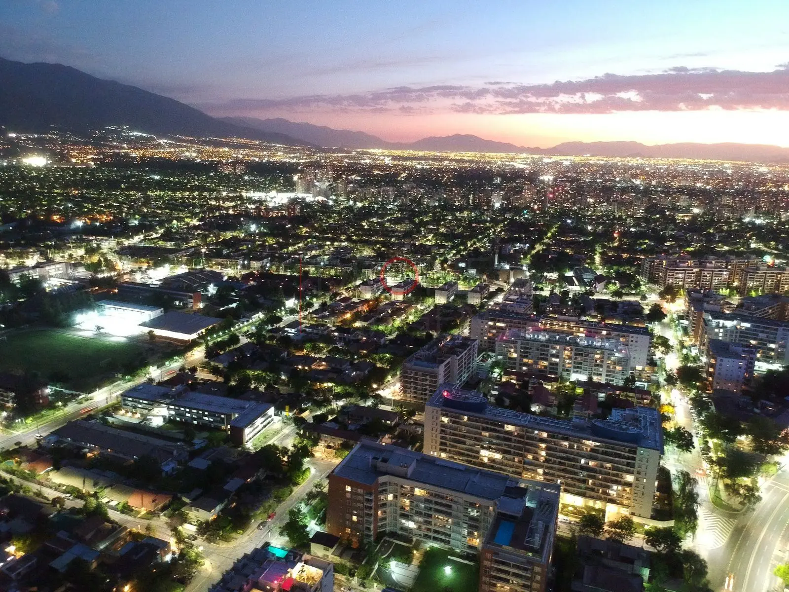 Ciudad iluminada bajo cielo de atardecer, Las Condes · vista aérea oblicua